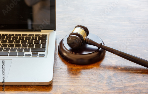 Judge gavel and a laptop, wooden background. Online auction concept