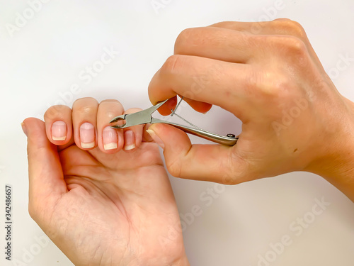 Close up of hands. Self manicure at home trimming cuticles on white background.