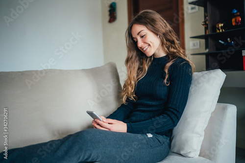 Giovane bella ragazza studente/ lavoratrice studia/ lavora da casa con il telefono. Smart working e distanza sociale. Lavorare con la tecnologia, social network e svago