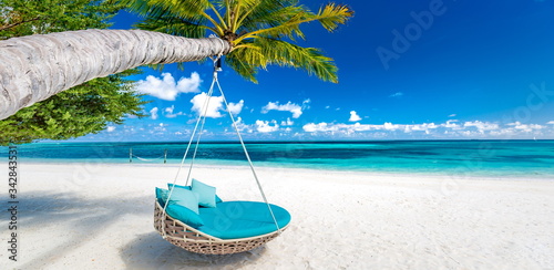 Tropical beach background as summer landscape with beach swing or hammock and white sand and calm sea for beach banner. Perfect beach scene vacation and summer holiday concept. Boost up color process 