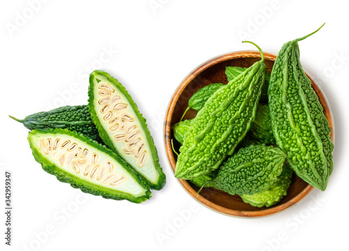 Closeup fresh bitter gourd ( cucumber, Momordica Charantia) in wooden bowl isolated on white background. Top view.