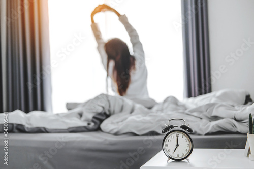Asian woman wake up on bed stretching feeling happy and fresh enjoying in the morning