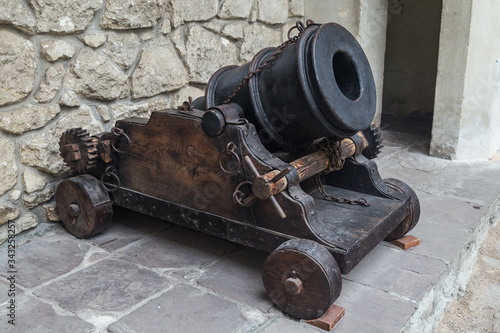 Old cannon over stone wall. Old castle. Ancient cannon on wheels. Museum piece outdoor.