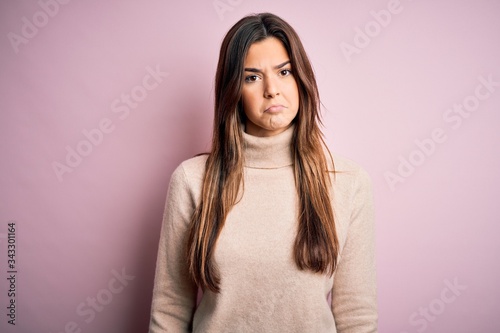 Young beautiful girl wearing casual turtleneck sweater standing over isolated pink background depressed and worry for distress, crying angry and afraid. Sad expression.