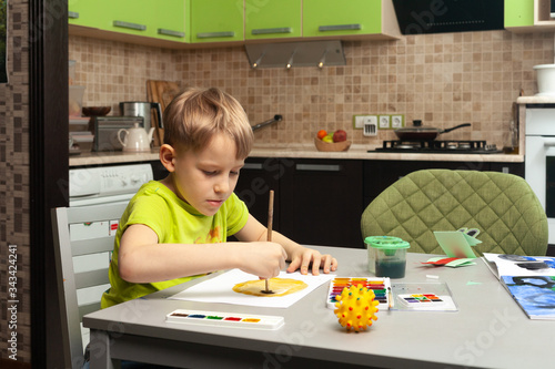 blond boy at home draws a coronavirus from nature (a visual representation of the virus in the form of a plastic ball). The concept of combating coronavirus. Self-isolation.