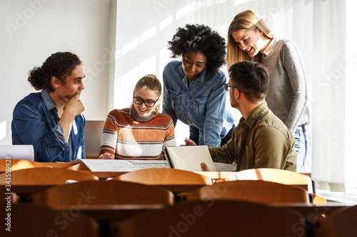 In the university classroom, a group of attentive students gathers, books and notes in hand, earnestly preparing for an upcoming lecture, eager to absorb knowledge and engage in meaningful learning.