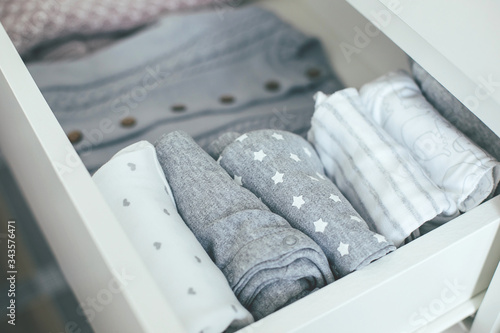 Top view of baby or newborn things of white, blue and grey colors are in the drawer. Lady fly system, kondo, konmary concept. Home lifestyle.