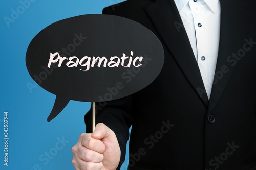 Pragmatic. Businessman in suit holds speech bubble at camera. The term Pragmatic is in the sign. Symbol for business, finance, statistics, analysis, economy