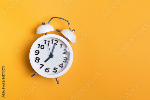 White vintage alarm clock on yellow color background
