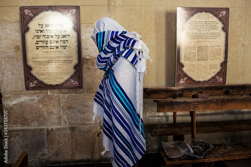 A Jewish man is covering himself with a Talit. Izaak Synagogue, Kazimierz.