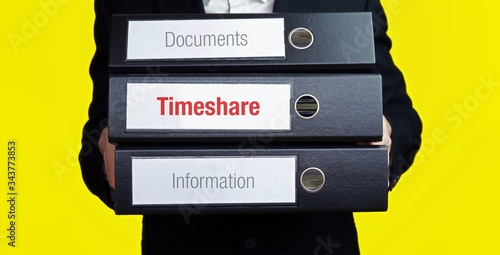 Timeshare – finance/economics. Man carries a stack of 3 file folders. A folder has the label Timeshare. Business, statistics concept