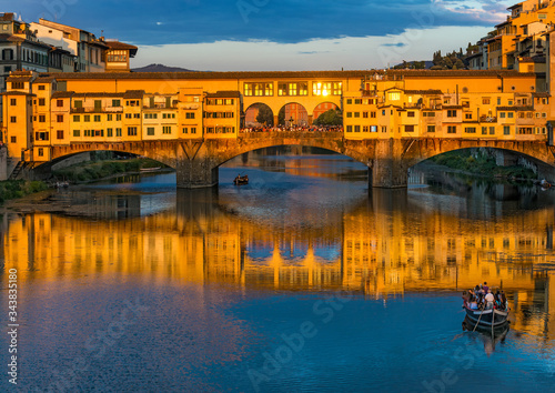 Florence Ponte Vecchio with two litte boats of "renaioli" floating on the Arno river at sunset