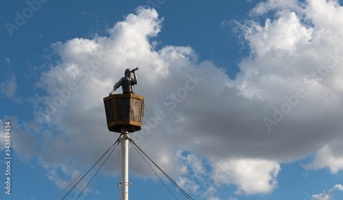 Statue of a pirate watching on the top of the ship through a monocular.