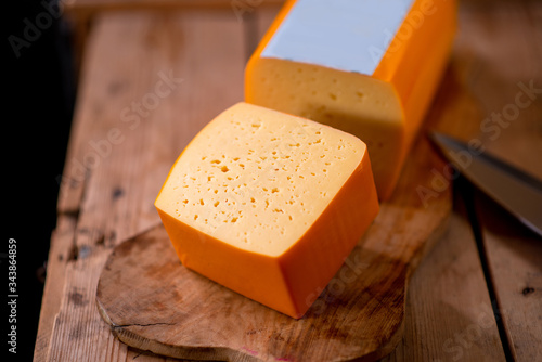 Medium hard cheese gouda edam on wooden board on sunlight table traditional table texture