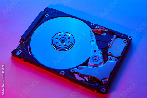 Disassembled hard drive from the computer, hdd with neon light. Opened hard drive Part of computer or laptop