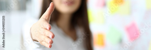 Cheerful female clerk welcoming business partner by shaking hand as sign of future achievements and prospects closeup