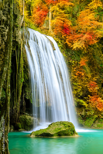 Colorful majestic waterfall in national park forest during autumn