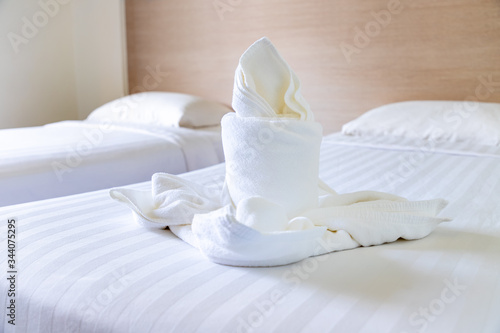 White towel folded into flower and candle shape on bed in hotel resort room to welcome guest