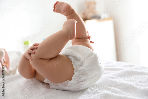 Cute little baby in diaper on bed