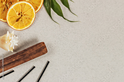 Incense sticks with a stand, sliced orange circles in a wooden bowl on a gray background. Also a seashell.Aromatherapy. The concept of home Spa.