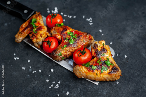 grilled chicken wings with spices on a knife on a stone background with copy space for your text