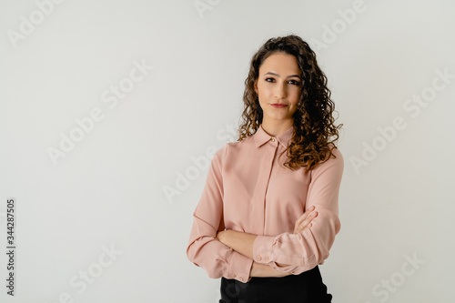 mujer de pelo morena con camisa elegante rosa con los brazos cruzados