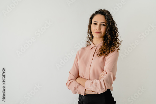 retrato de una chica morena con camisa elegante rosa con los brazos cruzados