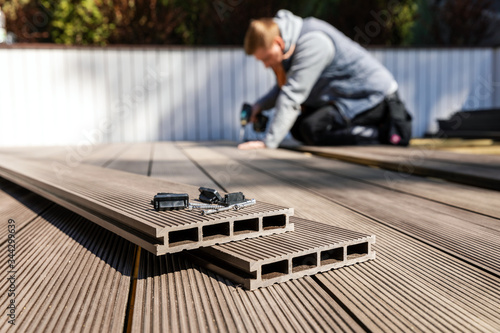 wpc terrace construction - worker installing wood plastic composite decking boards
