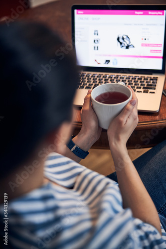 Caucasian girl in striped shirt working on laptop indoors