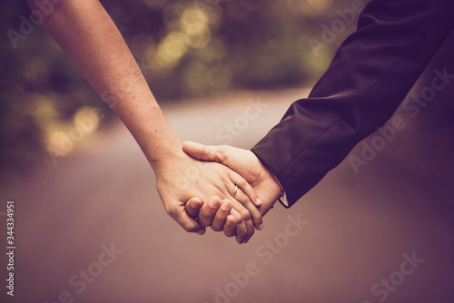 Wedding couple holding hands in sepia tone with path in background.