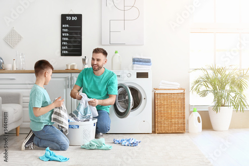 Man and his little son doing laundry at home