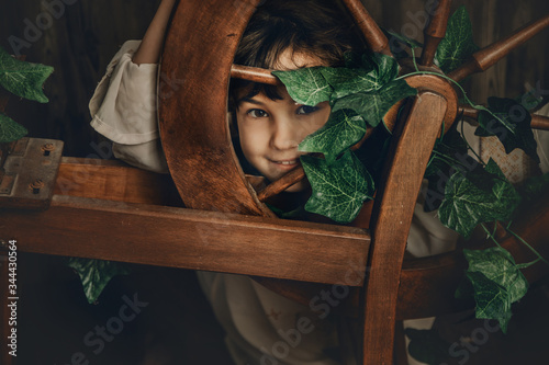 vintage portrait of young child girl with wool spinning wheel on wooden background