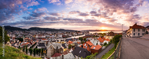 City or village in norway during sunset with sea clouds ships and sun in warm colors