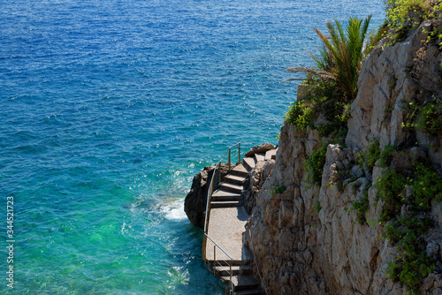 Scenic Fisherman Cove in Monaco / Monte-Carlo (Crique des Pêcheurs): Steps leading into colorful ocean (with space for text).