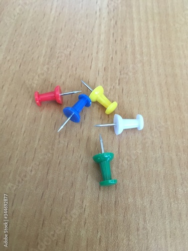 Colored push pins lie on a brown table