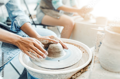 Close-up of female hands sculpting clay on a Potter's wheel. Concept of hobby and cretivity at home and in the Studio workshop