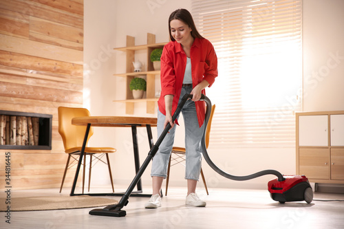 Young woman using vacuum cleaner at home