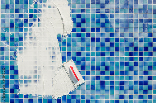 repairing and service of the pool. grouting tiles in the pool. Applying gap filling adhesive sealant or grout with a plastering trowel to the tiles in a swimming pool.