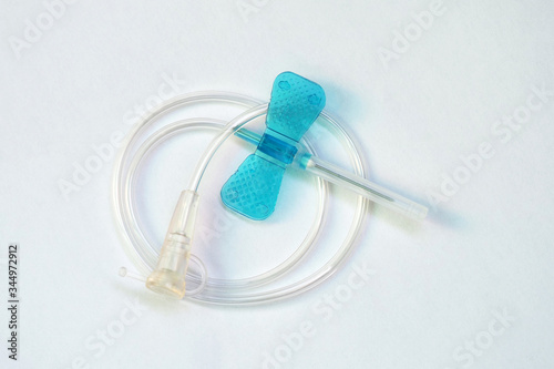 Blue butterfly catheter on light background. Butterfly dropper needle