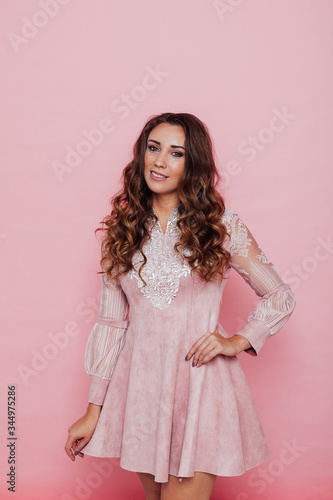 Portrait of a beautiful fashionable woman with hair curls in a pink dress