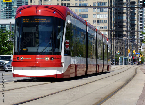 Toronto Harbourfront streetscape and urban scene. concrete and glass condominium buildings background. red streetcar. low angle perspective. bright summer day, steel tracks and light car traffic.