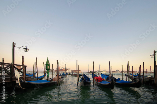 Several gondolas moored nearby Saint Mark square, early morning, tranquil sunrise atmosphere, usually serving tourists for transportation around the narrow canals, in Venice, Italy