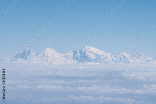 Cloudscape. Himalaya mountains rises above clouds. Clear blue sky. Photography made from window of airplane during flight to Nepal. Theme of beautiful landscapes.