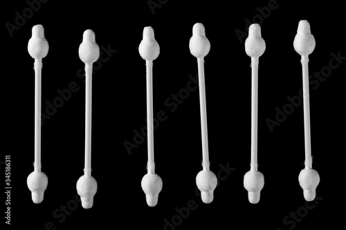 Cotton swabs for ear cleaning, hygiene product isolated on black background, top view