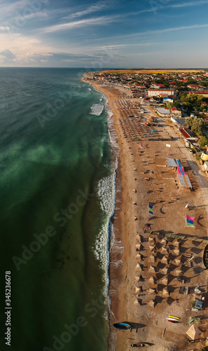 Aerial view of amazing beach with umbrellas and turquoise sea at sunrise. Black Sea at Vama Veche, Romania