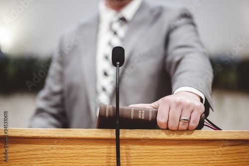 Male in a grey suit preaching words of the Holy Bible at the altar of a church