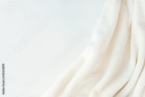 Soft cozy plush fabric with a pile lies in beautiful folds on white marble table. Vertical photo.