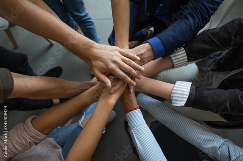 Close up mixed race business people putting hands together, support and unity concept. Diverse colleagues joining in team building activity, staff training concept, start working together, teamwork.