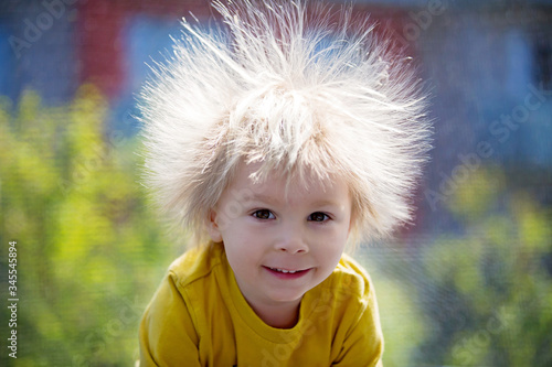 Cute little boy with static electric hair, having his funny portrait taken outdoors on trampoline