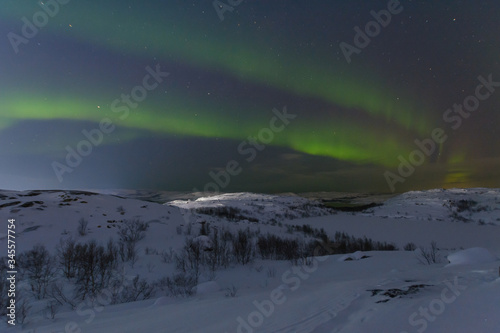 Aurora and stars in the sky .The rocks and ground are covered with snow.Arctic.